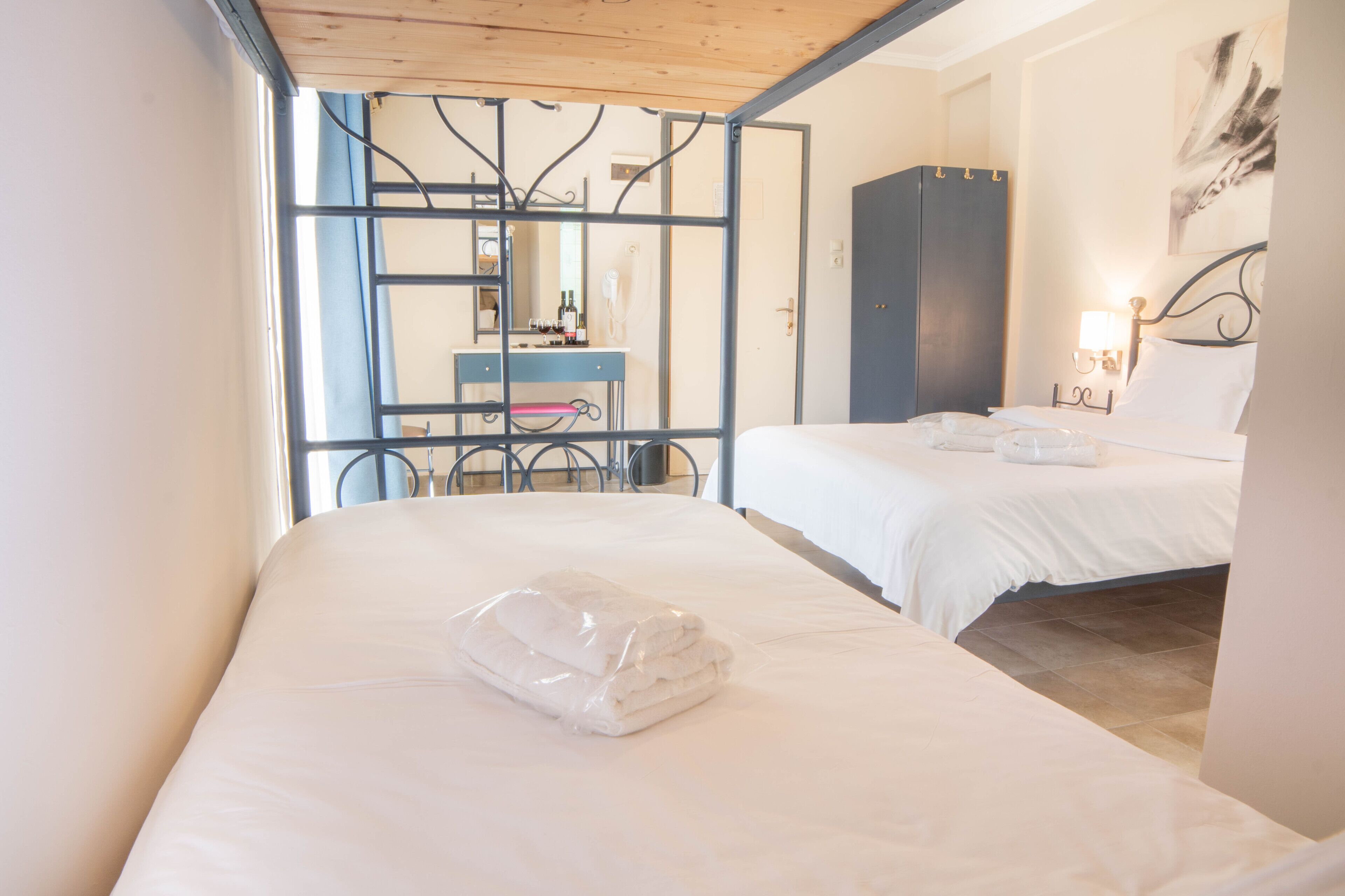 Habitación de hotel con dos camas, un escritorio y vistas a través de un panel de vidrio.