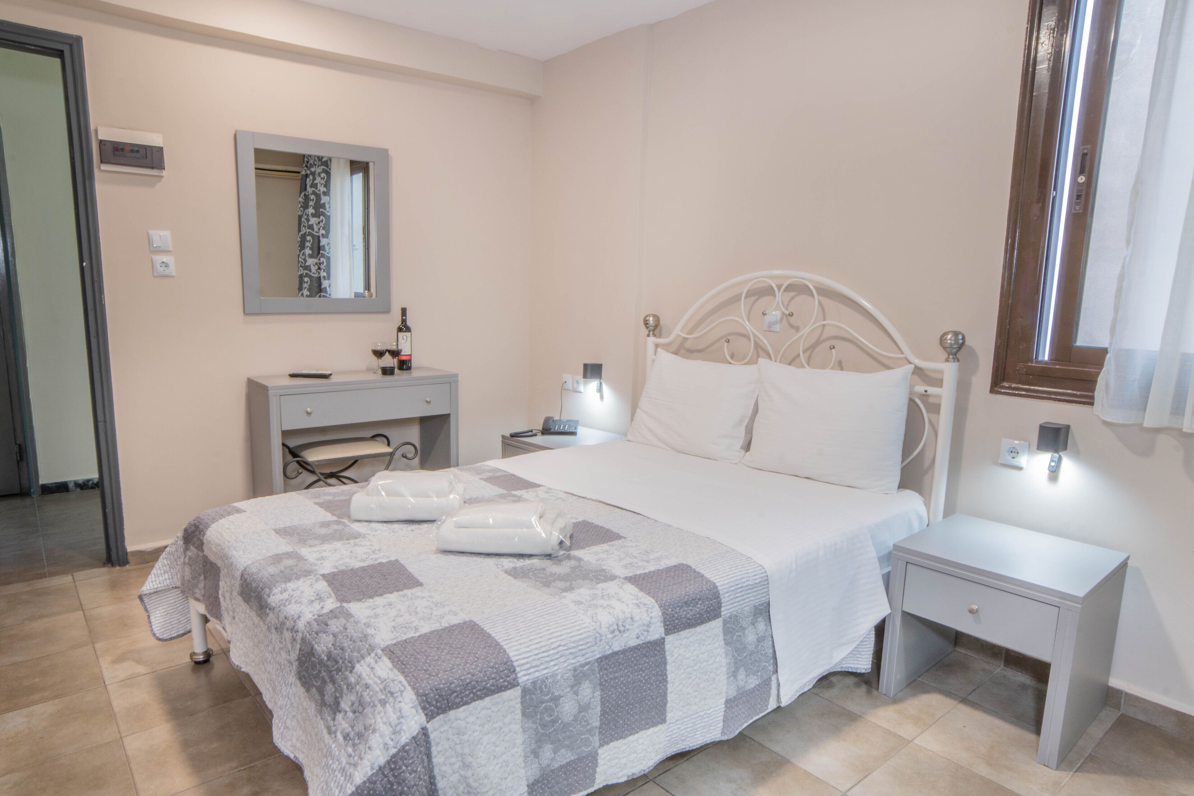 A neatly arranged bedroom with a bed, bedside tables, a mirror, and a desk with a chair.
