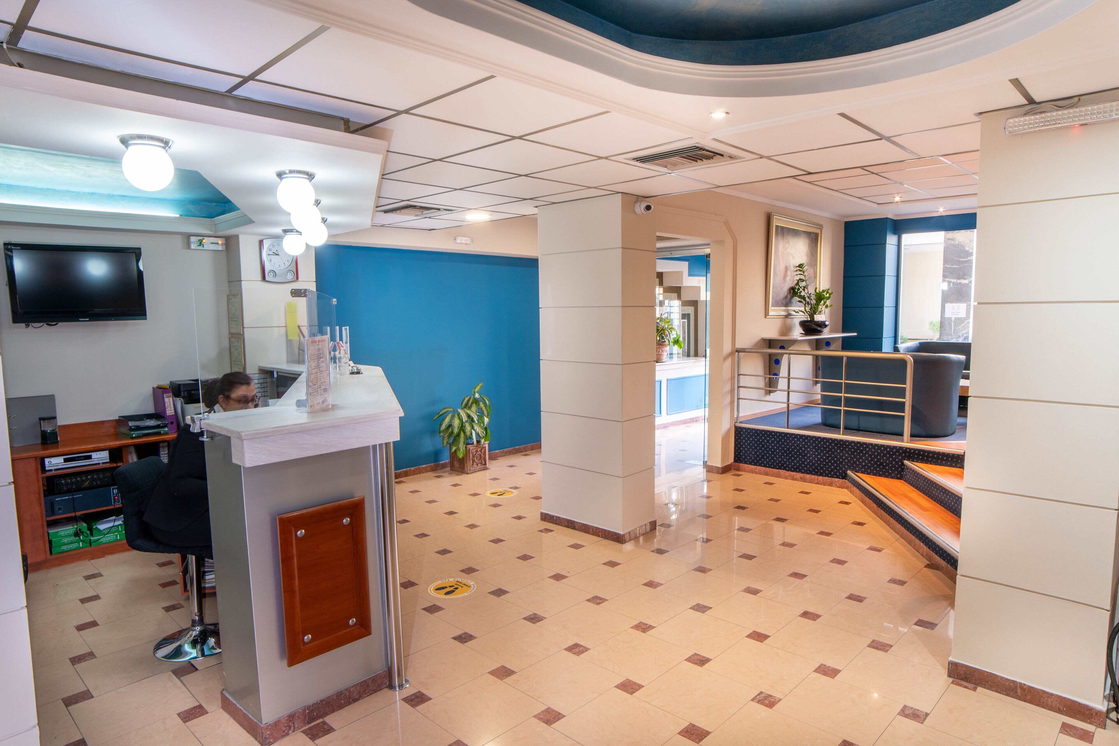 Un espace d’accueil avec un comptoir, un téléviseur et une horloge au mur.