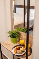Una mesa de madera con un desayuno que incluye pasteles, una planta verde y dos vasos de zumo de naranja.