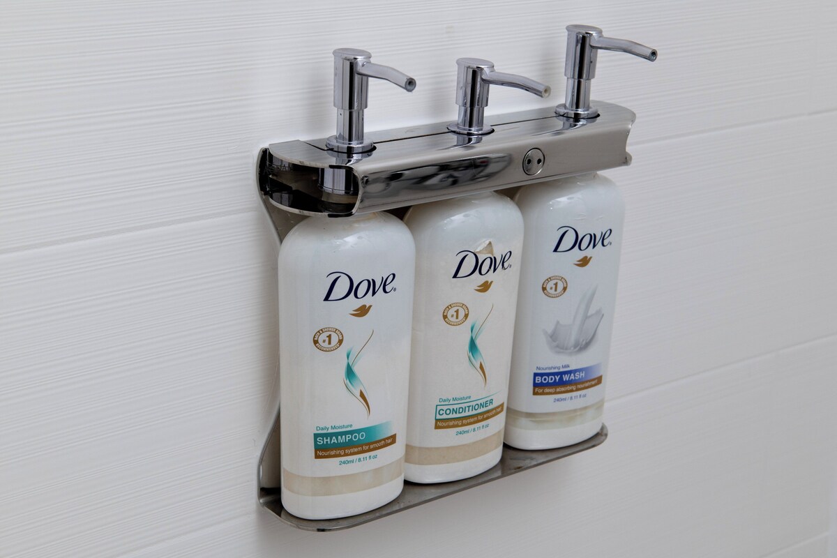 A shelf with three Dove body wash bottles.