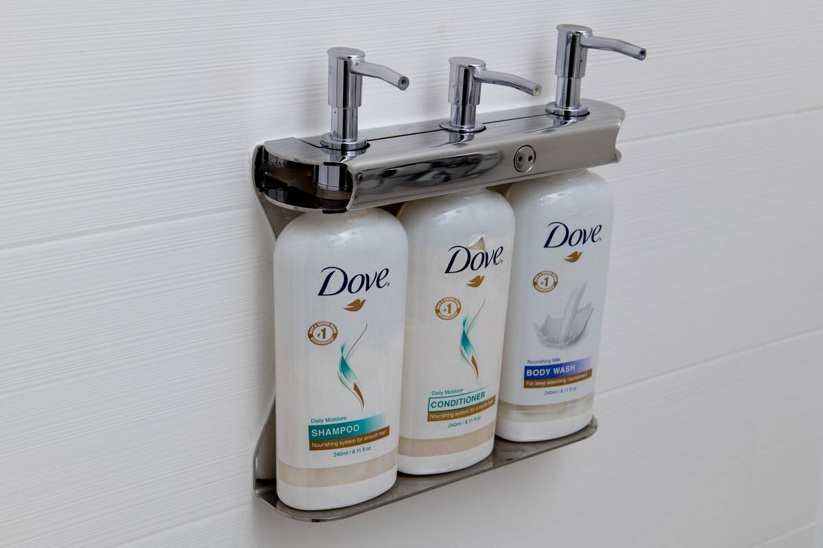 A shelf with three Dove body wash bottles.
