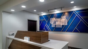 A reception desk with a modern design, a blue geometric wall panel, and a sign indicating a hotel name. - Holiday Inn Express Charleston-Kanawha City by IHG (Charleston)