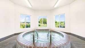 A hot tub with a view of a green landscape through three windows. - Best Western Nebraska City Inn (Nebraska City)