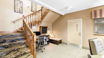 A home interior with a staircase, a desk with a computer, a bookshelf, a sofa, and a bed.