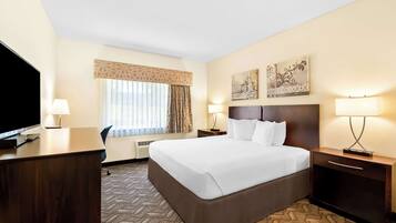 A hotel room with a large bed, a desk, a TV, and two lamps.