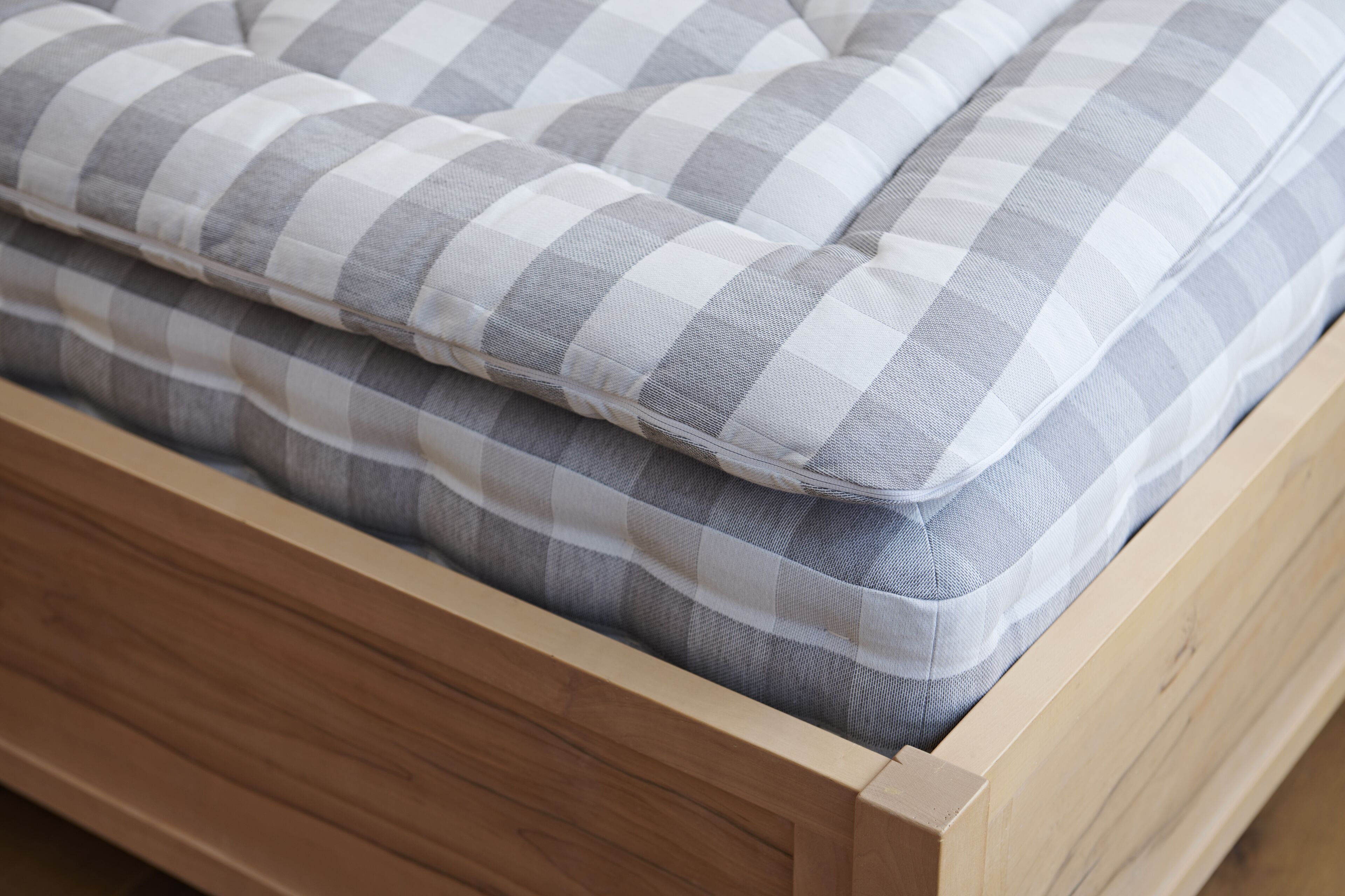 Una cama con colchón de cuadros y cabecero de madera.