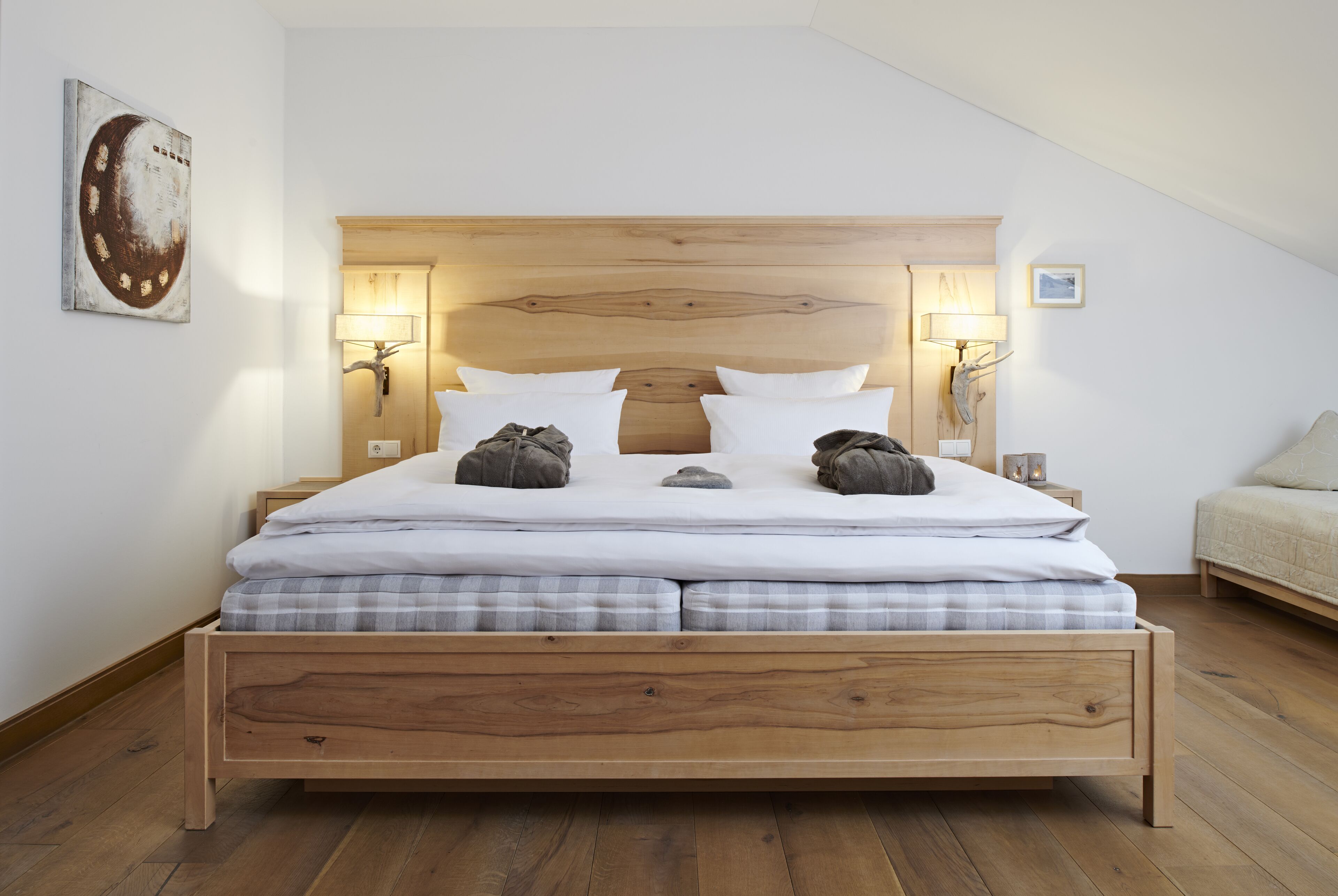 Un dormitorio moderno con estructura de cama de madera, ropa de cama blanca y dos lámparas de noche.