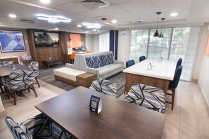 Habitación de hotel con comedor, sofá y un amplio ventanal.