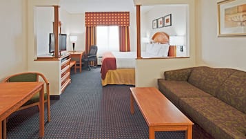 A hotel room with a bed, a sofa, a desk, a television, and a mirror.