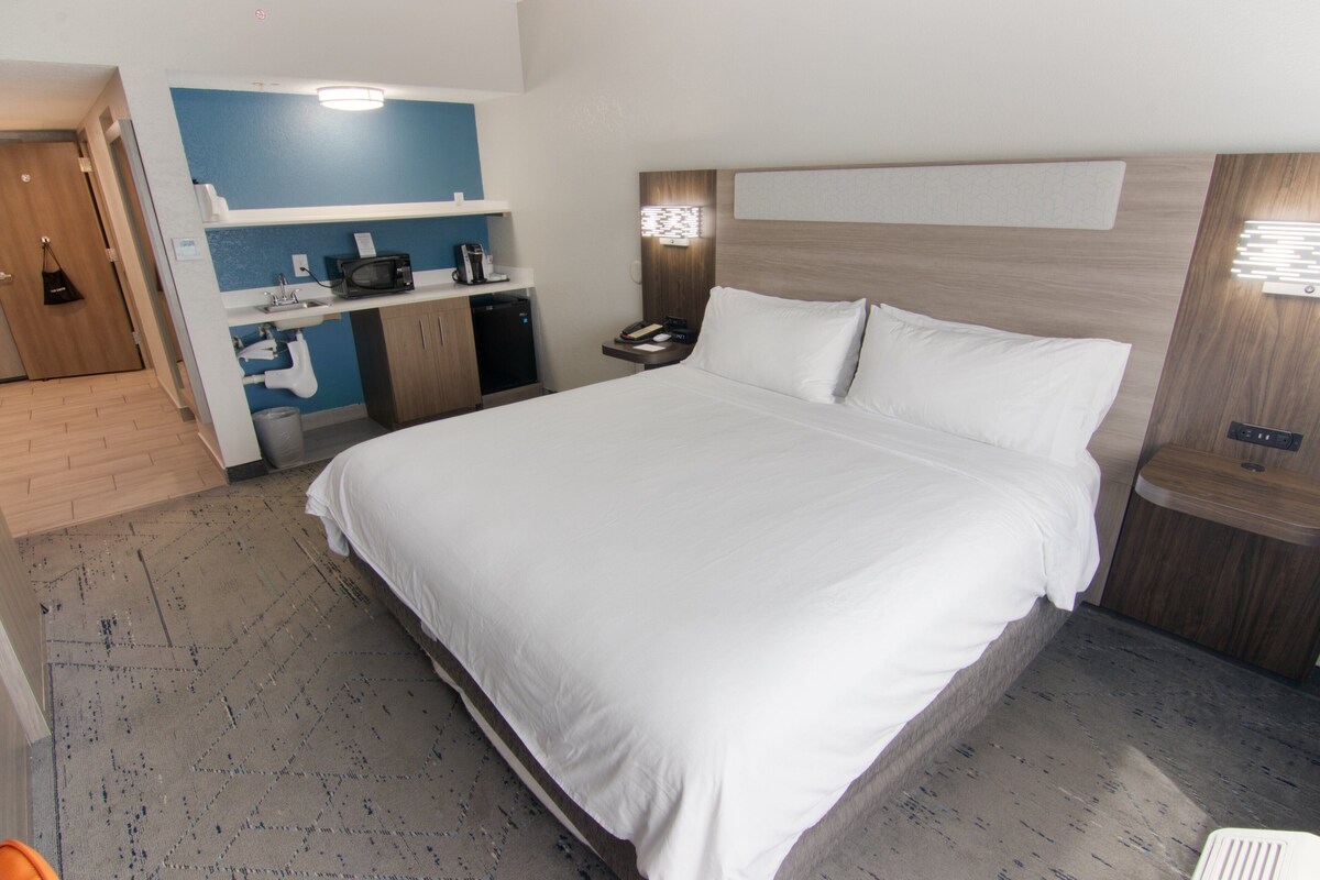 Una habitación de hotel con una cama grande, una kitchenette pequeña y un baño independiente.