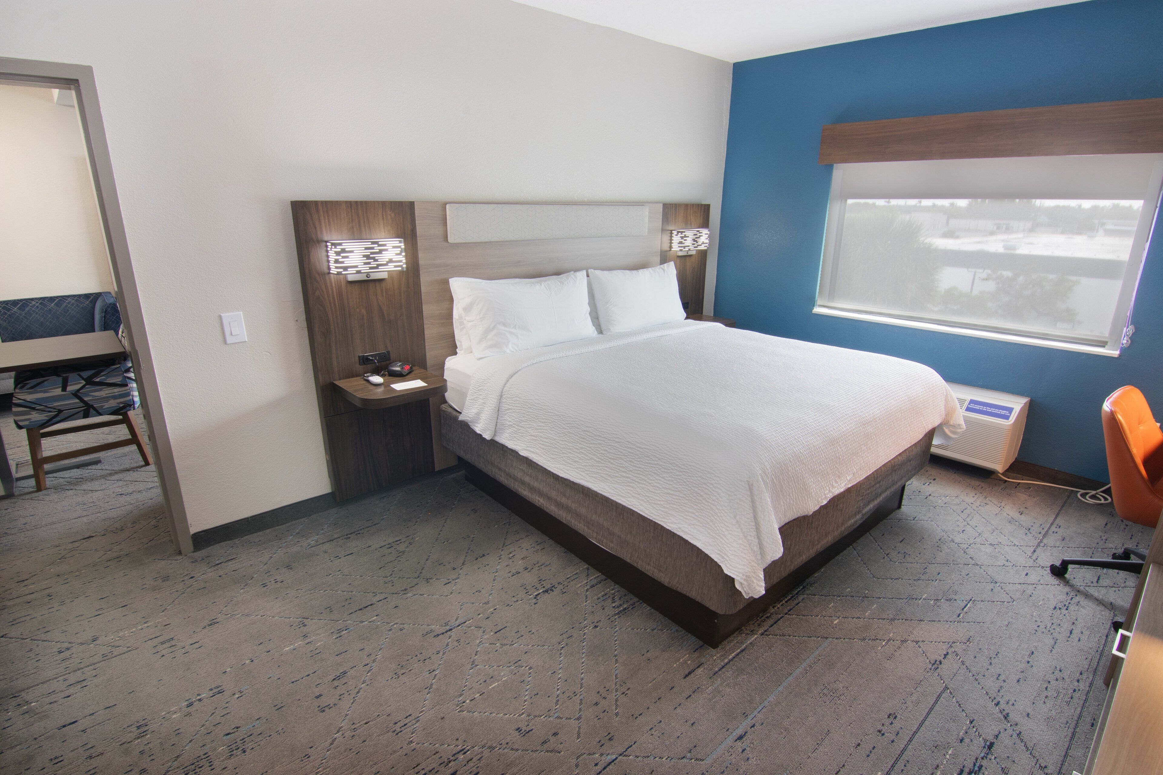 Een hotelkamer met een bed, nachtkastjes, een bureau en een raam.