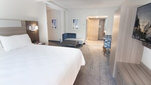 Una habitación de hotel con una cama grande, un escritorio, una silla y un televisor.