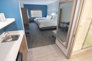 A hotel room with a kitchenette, two beds, a small table, and a shower area. - Holiday Inn Express & Suites Ft. Lauderdale Airport West by IHG (Davie)