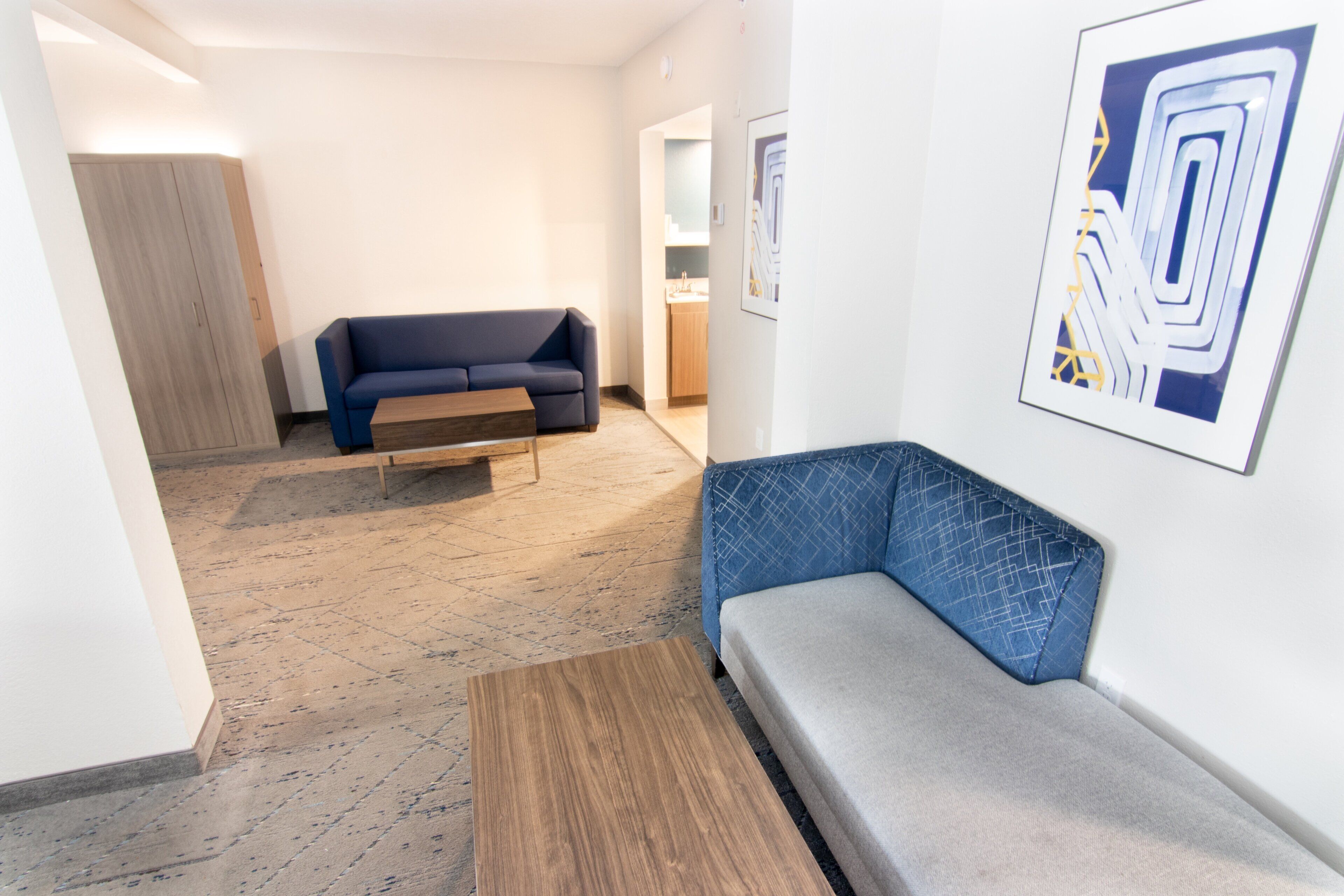 A modern interior with a blue sofa, a wooden coffee table, and a patterned wall art piece.