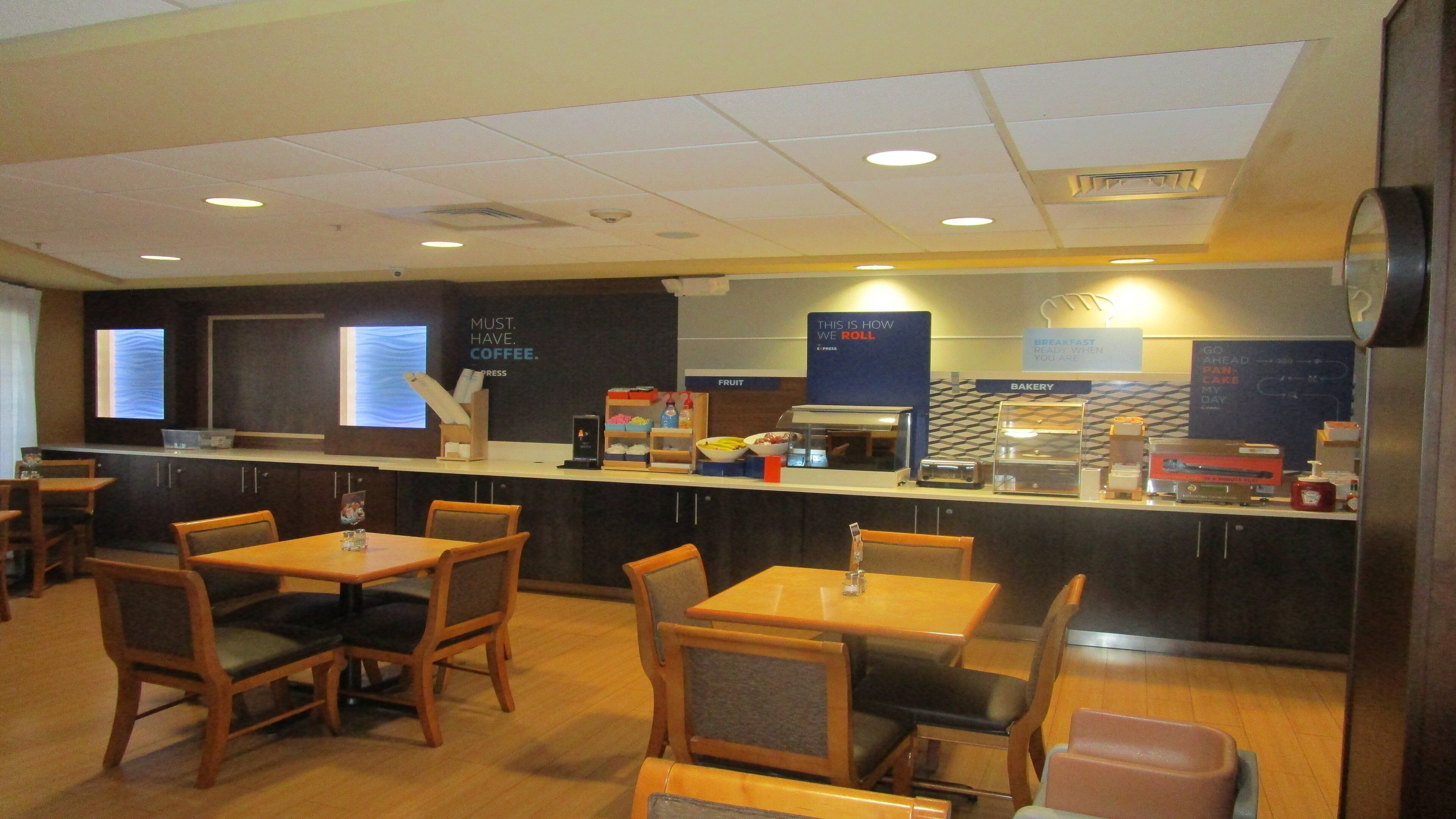 A cafe with tables and chairs, a counter with food and drink items, and signs indicating sections like 'fruit' and 'bakery'.