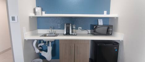 A compact kitchenette with a microwave, coffee maker, and sink.