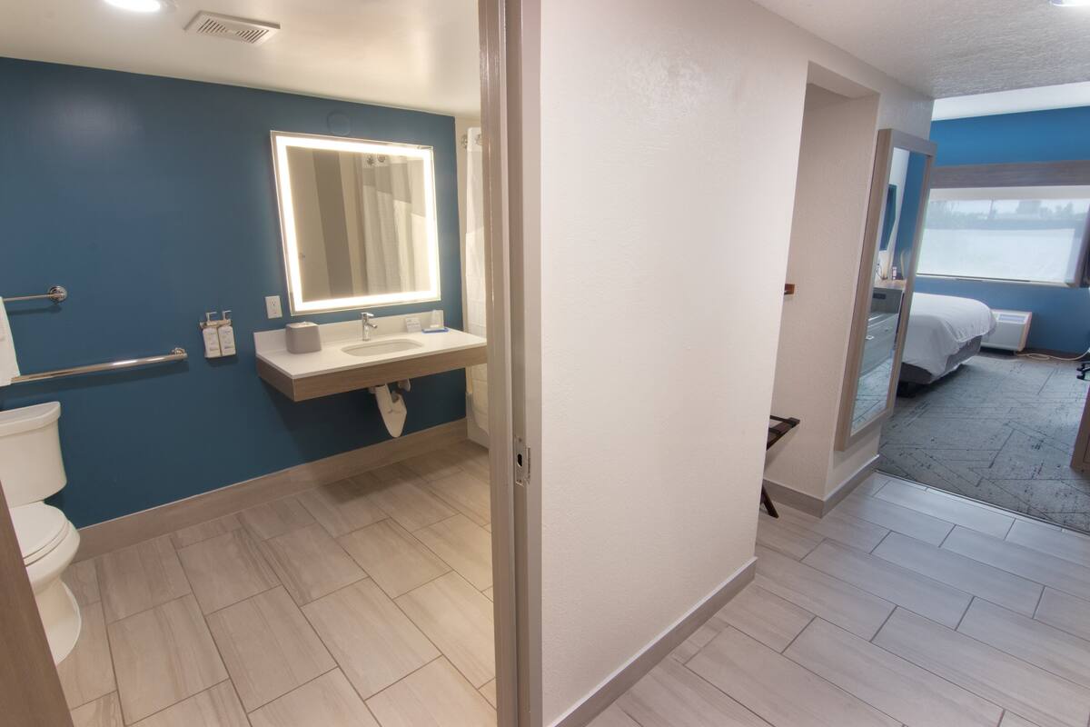 A modern bathroom with a large mirror, a sink, and a toilet.