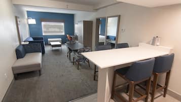 A modern hotel room with a large bed, a desk, and a seating area with a sofa and chairs.