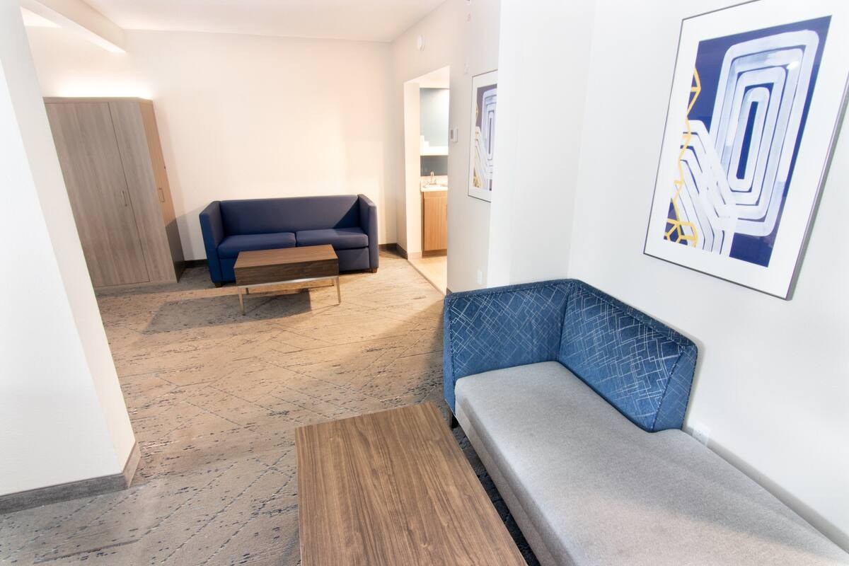 A modern living room with a blue sofa, a wooden coffee table, and a grey bench.