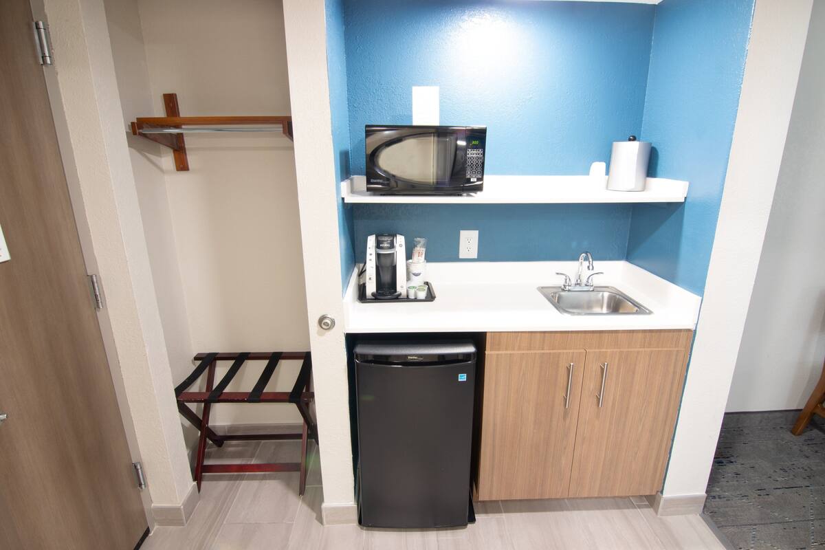 A compact kitchen with a microwave, sink, and a small refrigerator.