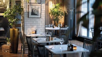Interior de un restaurante con paredes de azulejos blancos, suelo de madera y varias mesas dispuestas para comer.