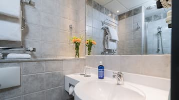 A modern bathroom with a large sink, a mirror, and a shower.