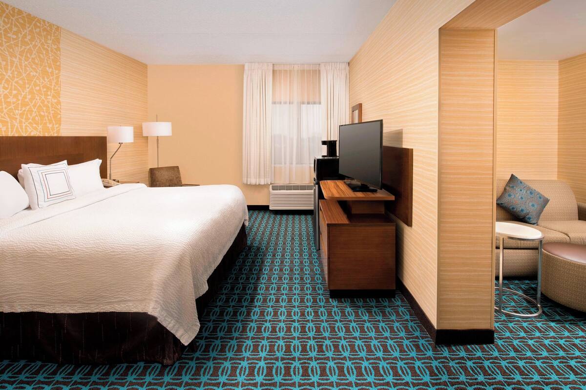 Une chambre d’hôtel avec un grand lit, un bureau avec une télévision, une chaise et une petite table.