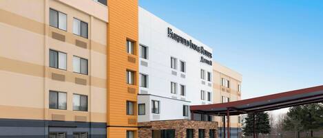 A hotel with a modern facade, multiple windows, and a covered entrance area.