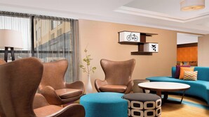 A modern living room with leather armchairs, a blue sofa, and a patterned ottoman. - Fairfield Inn & Suites Albany East Greenbush (East Greenbush)