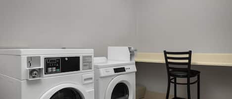 A laundry area with a washing machine, a dryer, and a chair.