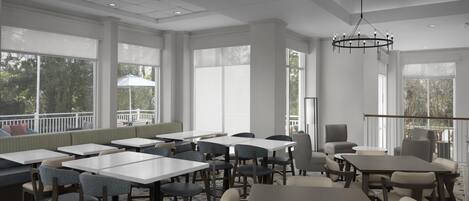 Un vaste espace dédié à la salle à manger, avec de nombreuses tables et chaises, de grandes fenêtres et un luminaire au plafond.