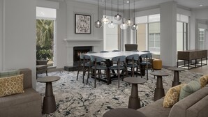 A spacious dining area with a large table, multiple chairs, and hanging pendant lights. - Hilton Garden Inn Hilton Head (Hilton Head Island)