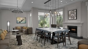 A spacious living area with a dining table, sofas, and a fireplace. - Hilton Garden Inn Hilton Head (Hilton Head Island)