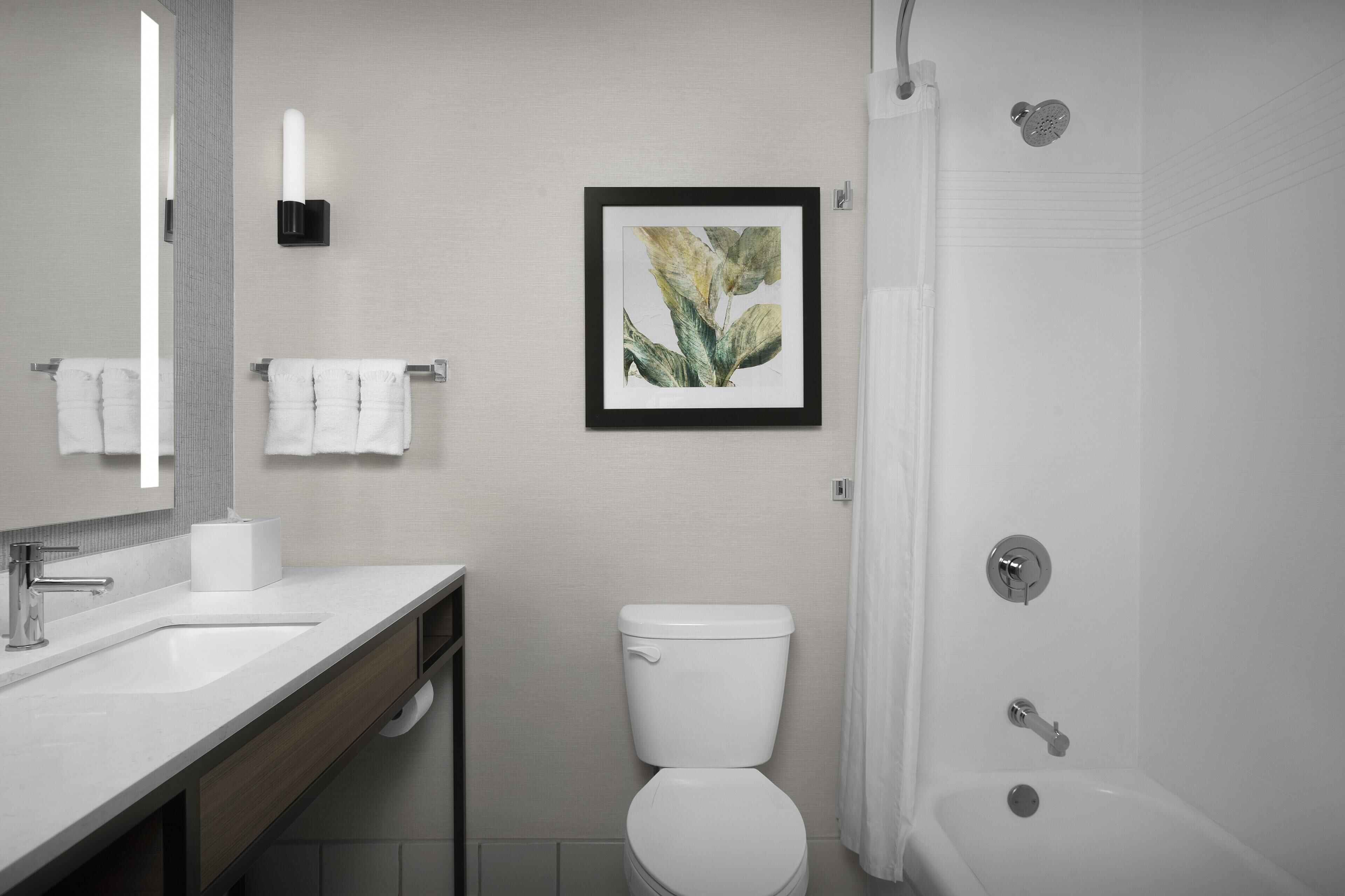 Un baño moderno con lavamanos, inodoro y ducha.