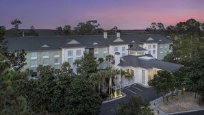 A large hotel with multiple buildings, a central tower, and a parking area surrounded by trees. - Hilton Garden Inn Hilton Head (Hilton Head Island)