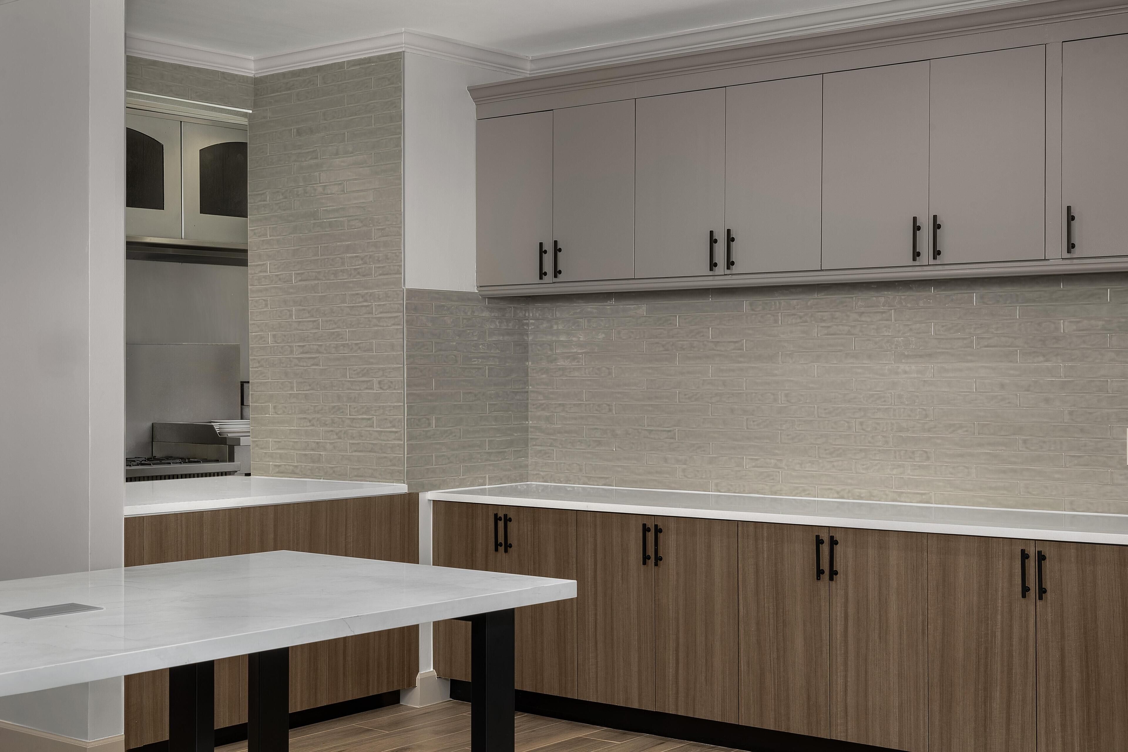A kitchen with a white countertop, wooden cabinets, and a brick backsplash.