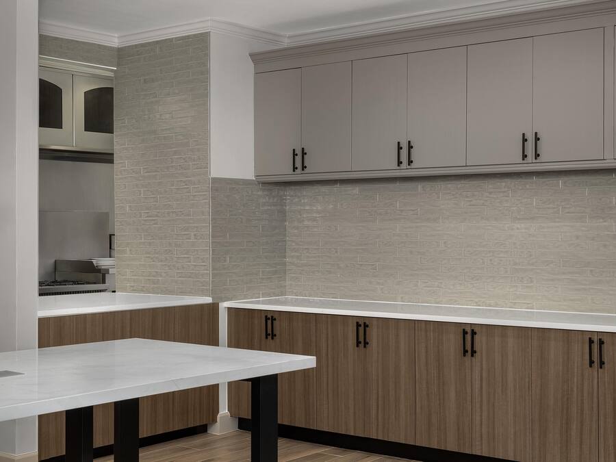 A kitchen with a white countertop, wooden cabinets, and a brick backsplash.