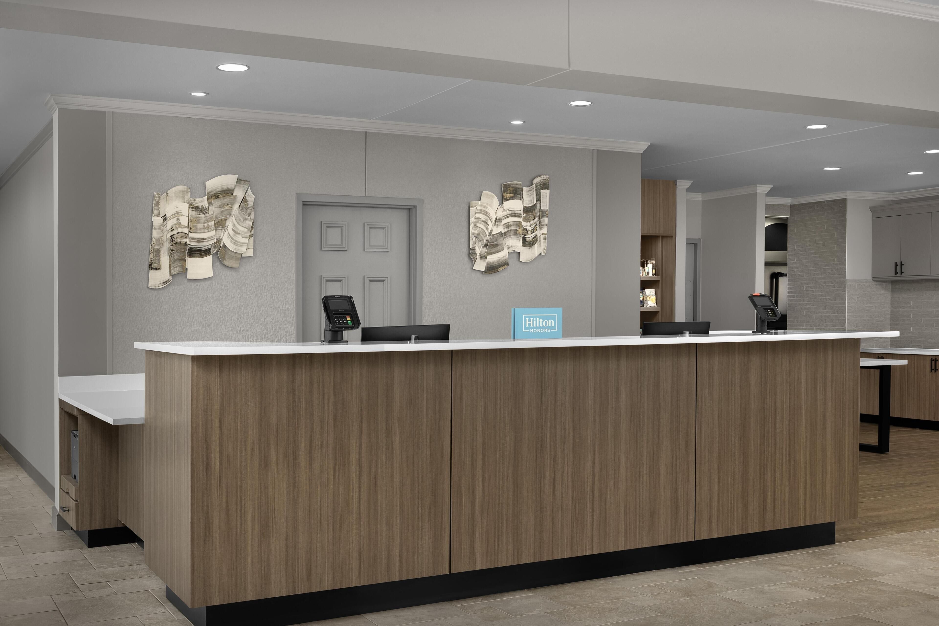 A hotel reception desk with a modern design, a counter, and a digital display.