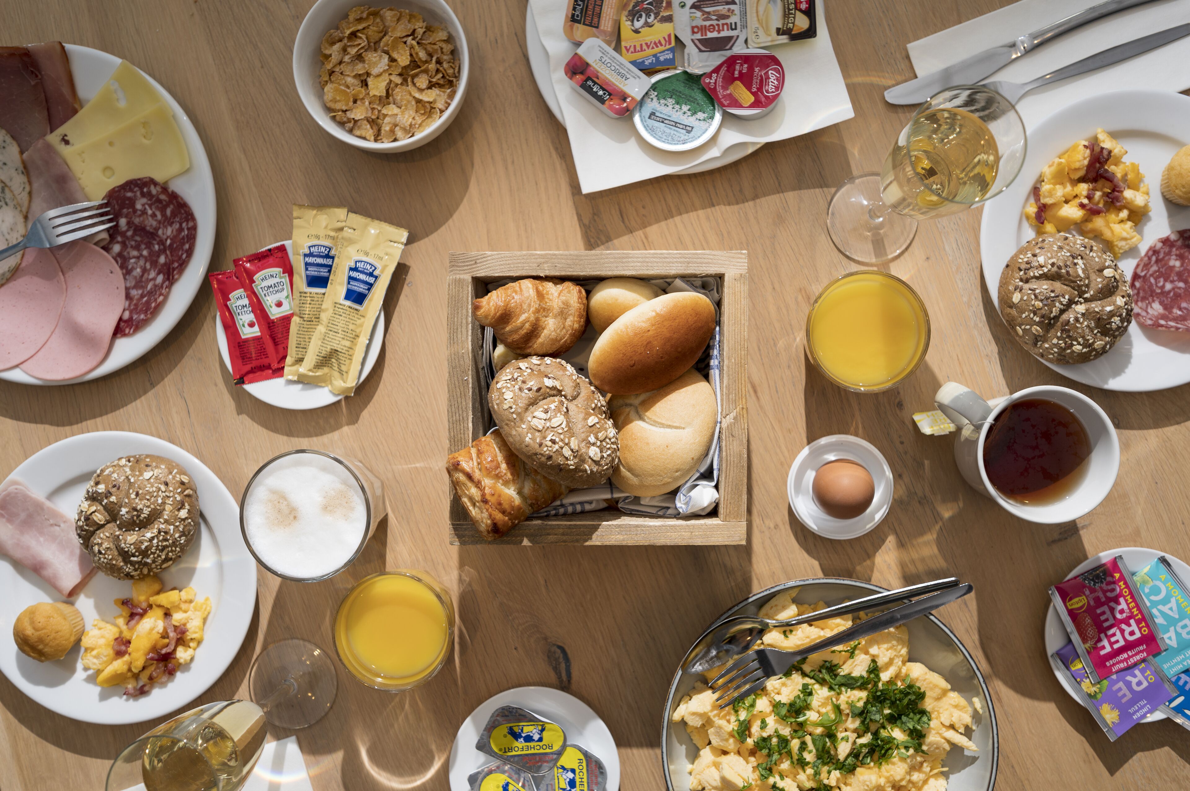 Une table de petit-déjeuner avec divers aliments, notamment des œufs, des saucisses et des viennoiseries.