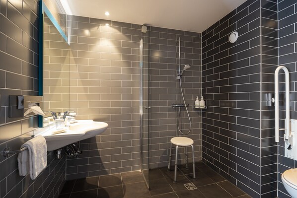 A modern bathroom with a glass-enclosed shower, a white sink, and a toilet.
