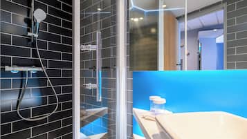 Une salle de bain moderne avec une douche à parois de verre, une baignoire blanche et un mur d’accent bleu.
