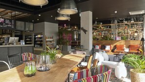 Een modern interieur met een houten eettafel, kleurrijke stoelen en een bar met planken en planten.
