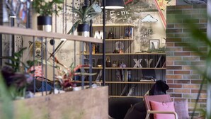 Een gezellig hoekje om te lezen, met een boekenkast, een stoel en een kleine tafel.