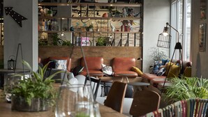 Een gezellige, goed verlichte zithoek met leren banken, een houten tafel en diverse decoratieve objecten.