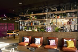 A modern lounge area with leather seating, a piano, and a variety of decorative items on shelves. - MOXY Berlin Humboldthain Park (Berlin)
