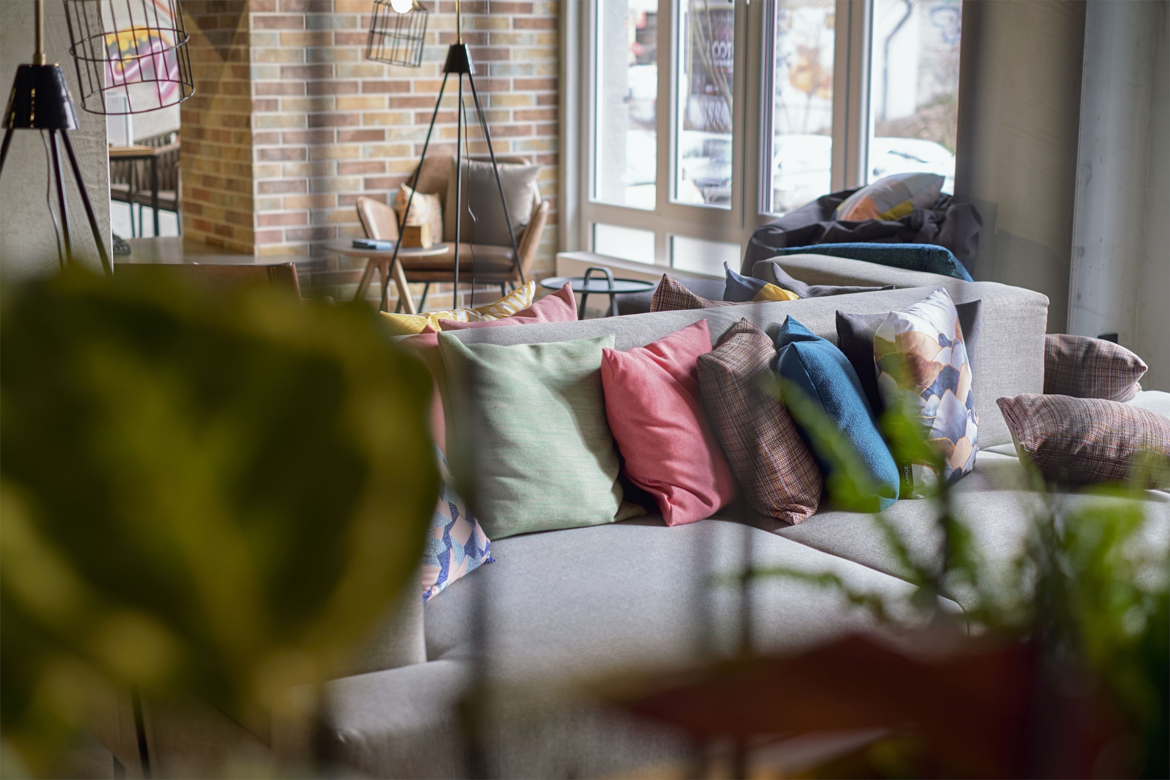 Ein gemütliches Wohnzimmer mit einer Couch, verziert mit bunten Kissen, einem Hängesessel und einer Ziegelwand.