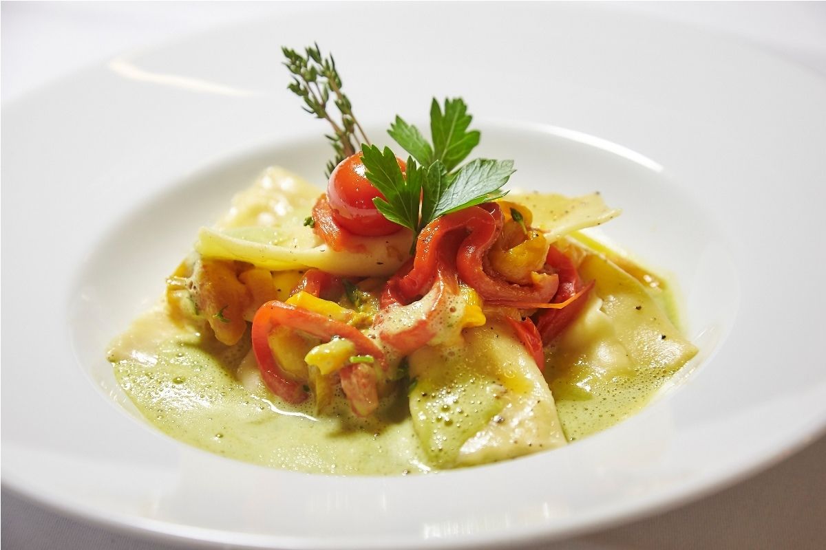 A plate of food with pasta, tomatoes, and a garnish.