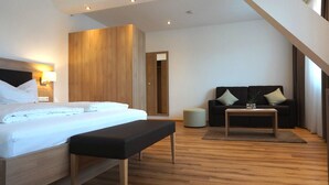 Una habitación de hotel moderna con una cama grande, un banco, un sofá, una mesita y una pared decorativa de madera.