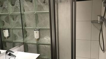 A bathroom with a glass partition wall, a white sink, and a shower area.